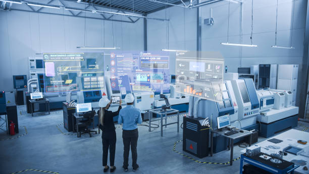 Control Room Industry 4.0 Factory: Two Engineers Uses Digital Tablet Computer with Augmented Reality Software to Connect with High-Tech Machinery, Robot Arm and Visualize Maintenance and Diagnostics of Equipment